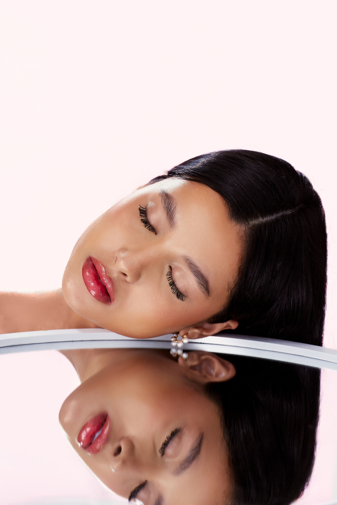 Woman resting on a mirrored surface with glowing skin